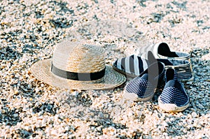 Straw hat and espadrilles lying on the sand on the beach. Summer concept. Holiday relaxing, beach vacation.