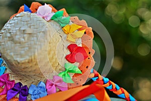 A straw hat filled with small colored ribbons and orange lace and ribbon braid