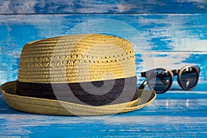 straw hat and glasses on wooden blue background