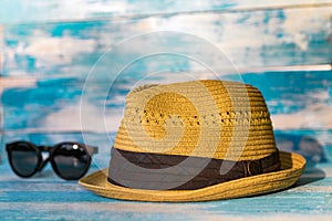 Straw hat and glasses on wooden blue background