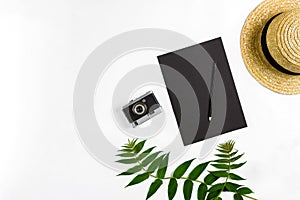 Straw hat with green leaves and old camera on white background, Summer background. Top view