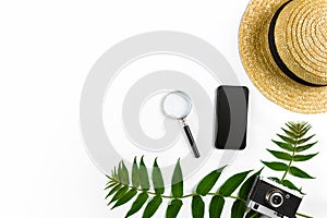 Straw hat with green leaves and old camera on white background, Summer background. Top view
