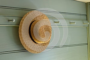 A straw hat hanging on a peg