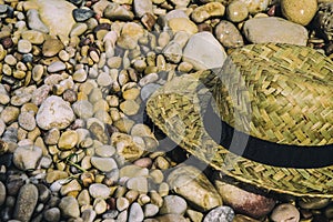 Straw hat lying on top of beach stones photo
