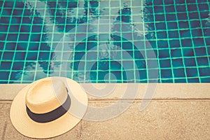 Straw hat at the pool edge with palm reflections in the water