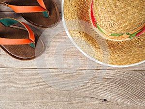 Straw hat and slippers on wooden table. Top view. Summer vacation planning concept