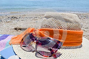 Straw hat, sunglasses and a book on the beach with sea in backgo