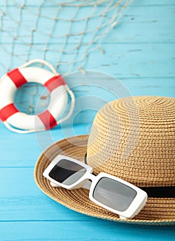 Straw hat, sunglasses and lifebuoy on blue background. Summer holiday, vacation, travel concept