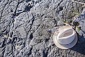 Straw hat with sunglasses lying on a stone.
