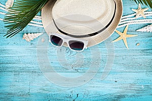 Straw hat, sunglasses, palm leaves, rope, seashell and starfish on blue wooden table top view in flat lay style. Summer holidays.