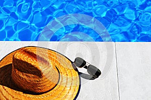 Straw hat and sunglasses by pool