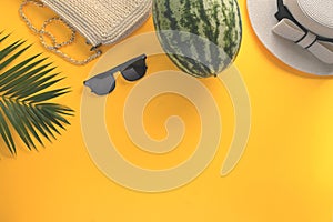 Straw hat, sunglasses, watermelon and palm leaf on yellow background. Summer and travel vacation concept
