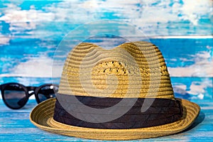 Straw hat and sunglasses on wooden blue background