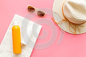 Straw hat and suntanning lotion on towel. Skin care with UV protection cosmetic