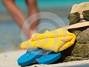 Straw hat, towel beach sun glasses and flip flops on a tropical
