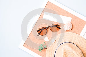 straw hat, toy palm tree, sunglasses, shells and a cardboard rectangle for your text on a corkboard