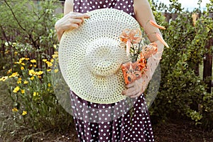 straw hatand a bouquet of tiger lily Lilium lancifoliumin hands of woman