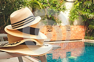 Straw hats stack at the pool edge with palm reflections in the water. Private pool in the asian style garden