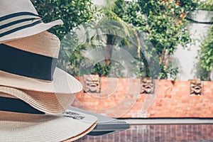 Straw hats stack at the pool edge with palm reflections in the water. Private pool in the asian style garden