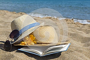 Straw hats, sunglasses and a book on the beach. Summer vacation