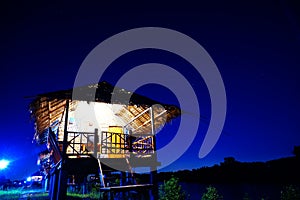 Straw house near small lake with sky in nightime, countryside photo