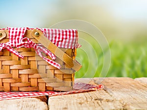 Straw picnic basket on a wooden table against the background of green grass, nature. The concept is summer vacation, picnic,