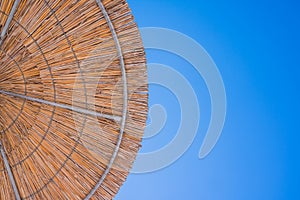 Straw roof of sun umbrella against the blue sky. Vacation topic.summer beach, background for an inscription.Texture of