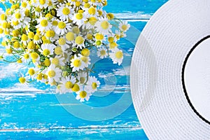 Straw Sun Hat Bouquet of Freshly Picked Camomile Flowers on Blue Weathered Plank Wood Garden Table. Spring Summer Countryside