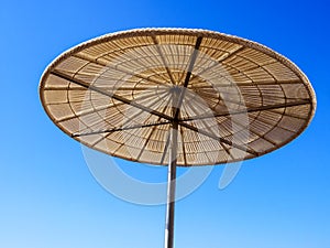 Straw sunshade in sunny summer day, tropical background