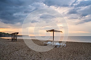 Straw sunshades and sunbeds on the empty sandy beach