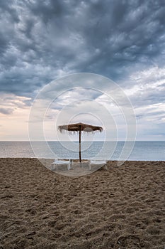 Straw sunshades and sunbeds on the empty sandy beach