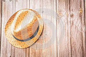 A straw trilby style summer hat on a rustic wood background with copy space