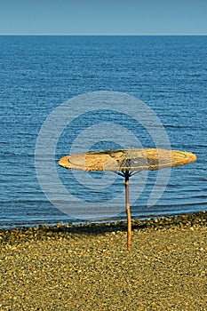 Straw umbrella in the morning on the beach by the sea