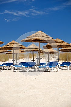 Straw umbrellas with beach chairs