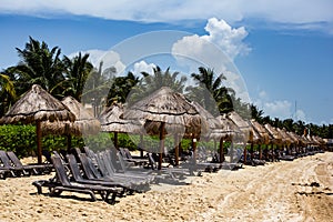 Straw Umbrellas relaxation lounge chairs set up on tropical bnea