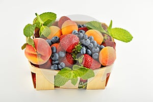 Strawberries, apricots, blueberries, peach in basket isolated on