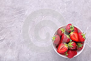 Strawberries in bawl on grey concrete background