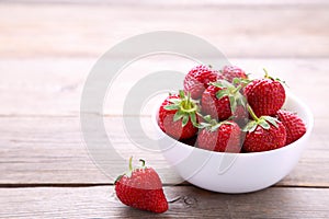 Strawberries in bawl on grey wooden background