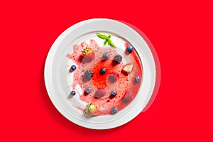Strawberries and blackberries on defrosted popsicle over a red background