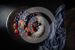 Strawberries and blueberries in a metal bowl on the tabl photo