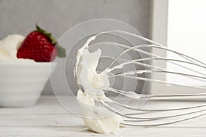 Strawberries in bowl with whipped cream and wire whisk