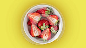 strawberries in a bowl on yellow background top view