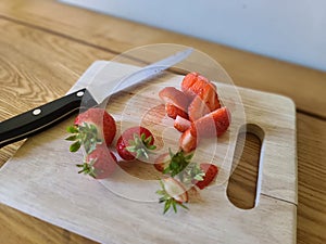 Strawberries on a chopping board with a knife