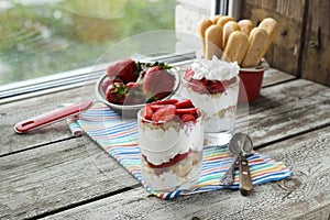 Strawberries dessert with biscuit and cream served on glasses