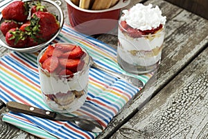 Strawberries dessert with biscuit and cream served on glasses