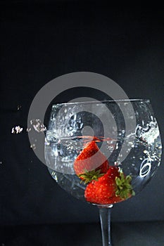 Strawberries dropping to a glass water splash