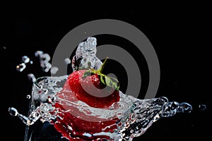 Strawberries fall into a glass of water.