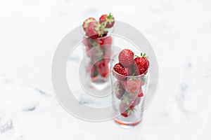 Strawberries in a glass cup on a white background with texture. Summer juice concept