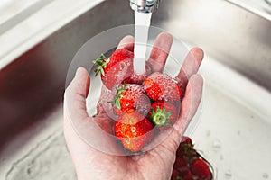 Strawberries in hands under the water. Pure fruit is health