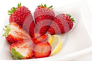 Strawberries and Lemmon on white plate photo